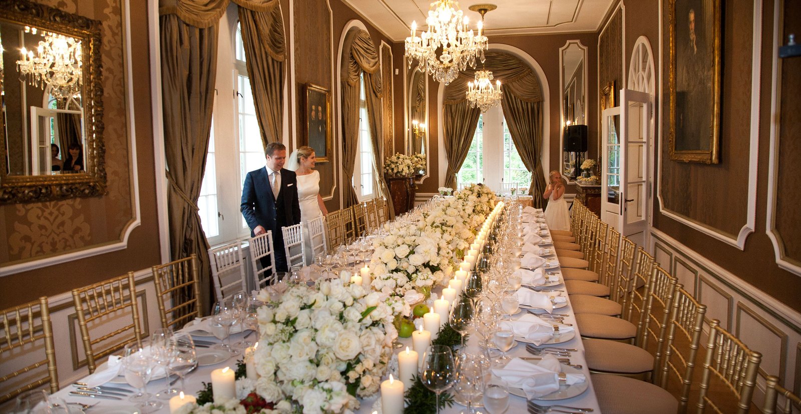 An elegant castle dinner setting with beautiful flowers and paintings, as the newlyweds make their entrance.