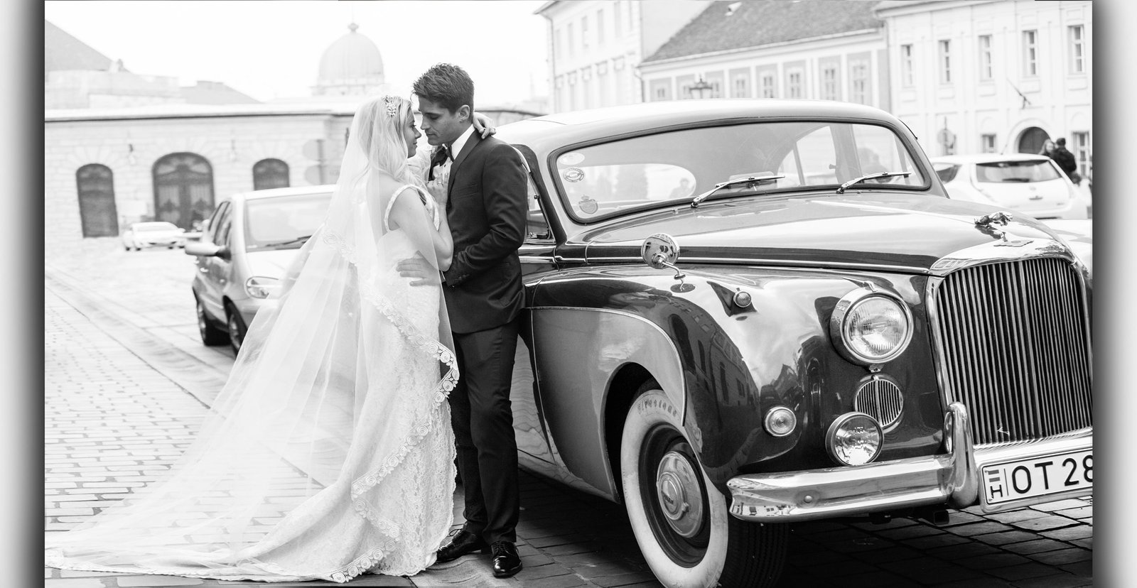 The bride and groom next to an elegant vintage Jaguar in the Buda Castle.