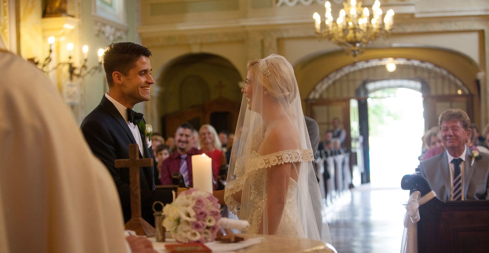 The bride and groom at the church ceremony, sharing an emotional, genuine smile that shows their love.