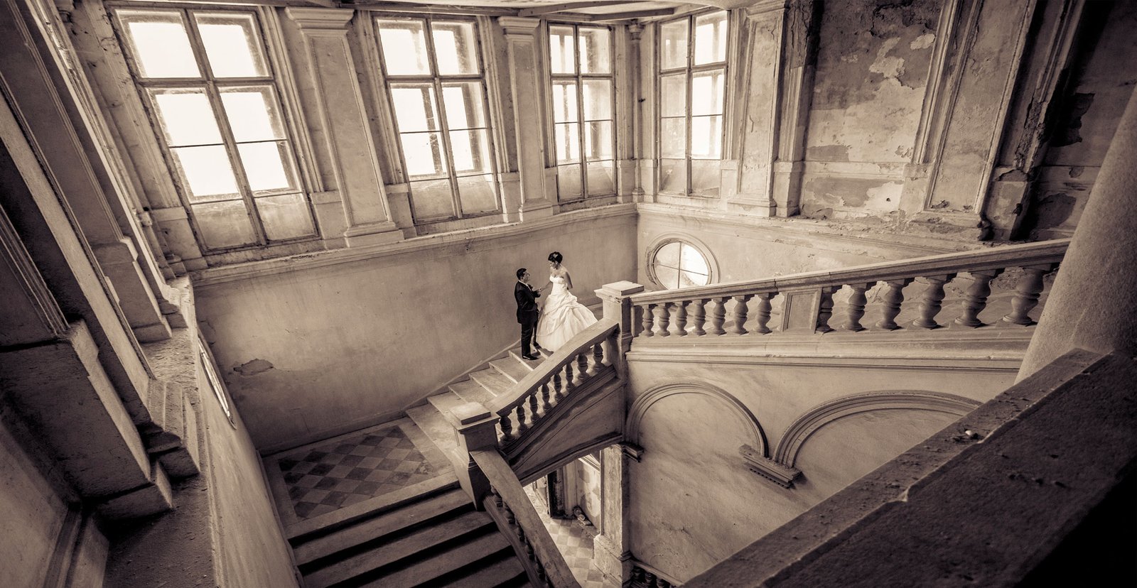 The bride and groom are posing on a grand staircase in an abandoned castle, a truly unique location.