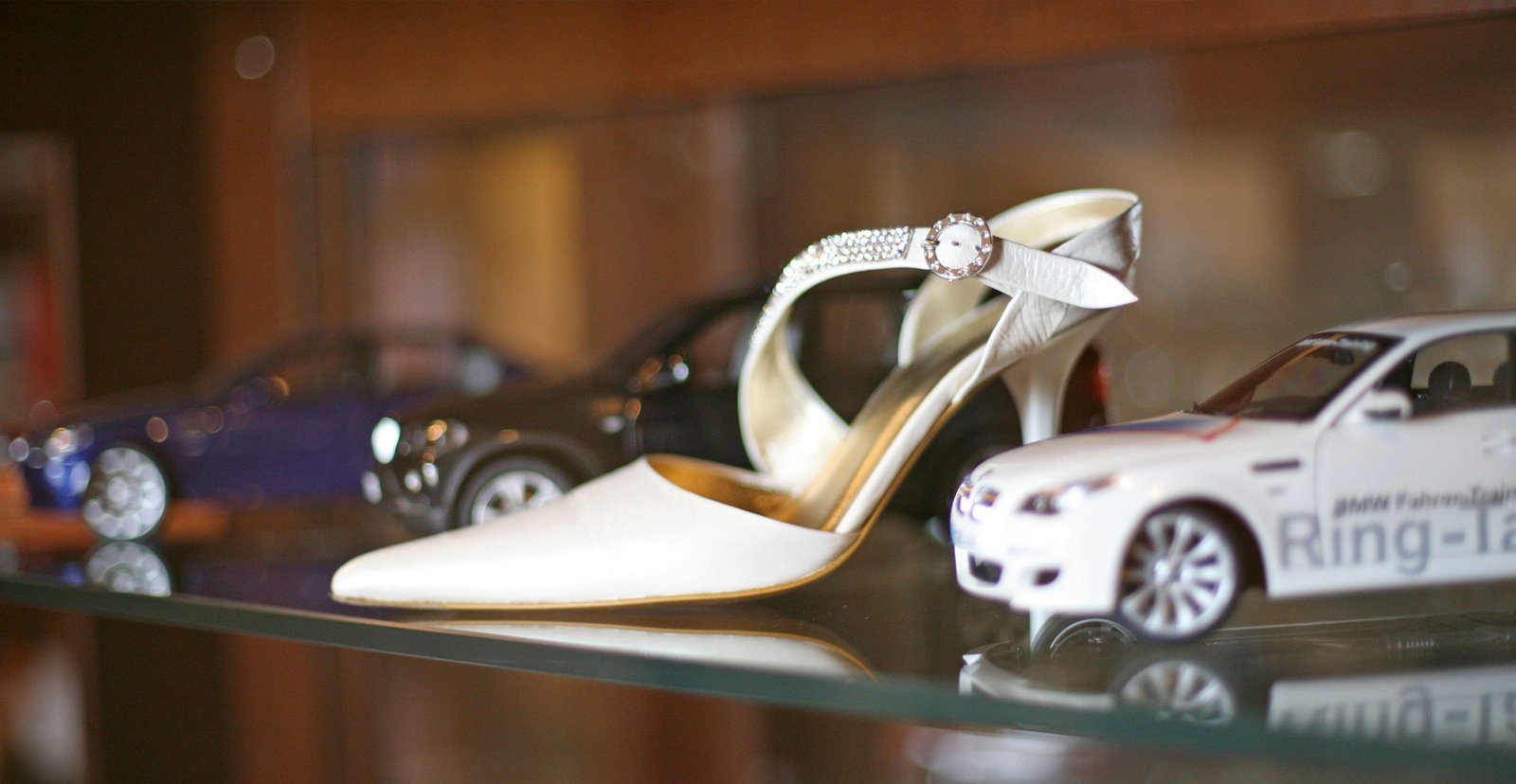 A woman's shoe between two model cars, a playful moment enjoyed by both men and women.